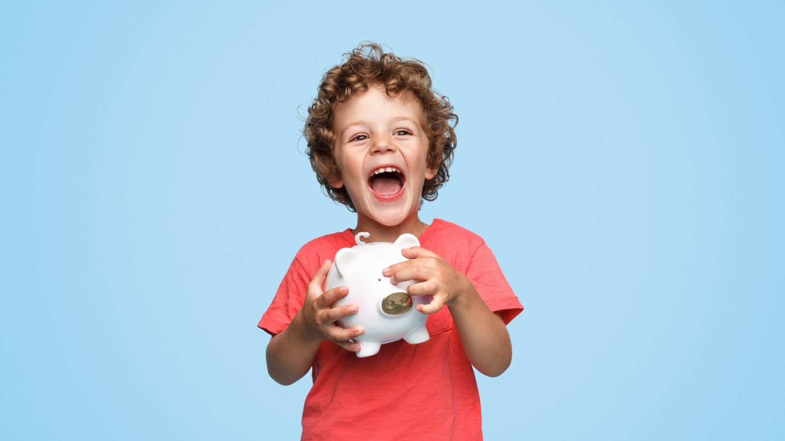 Un enfant souriant serre une tirelire dans ses mains